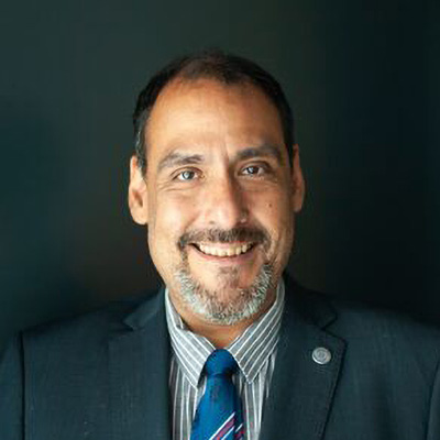A man wearing a suit and tie with a pleasant expression on his face.
